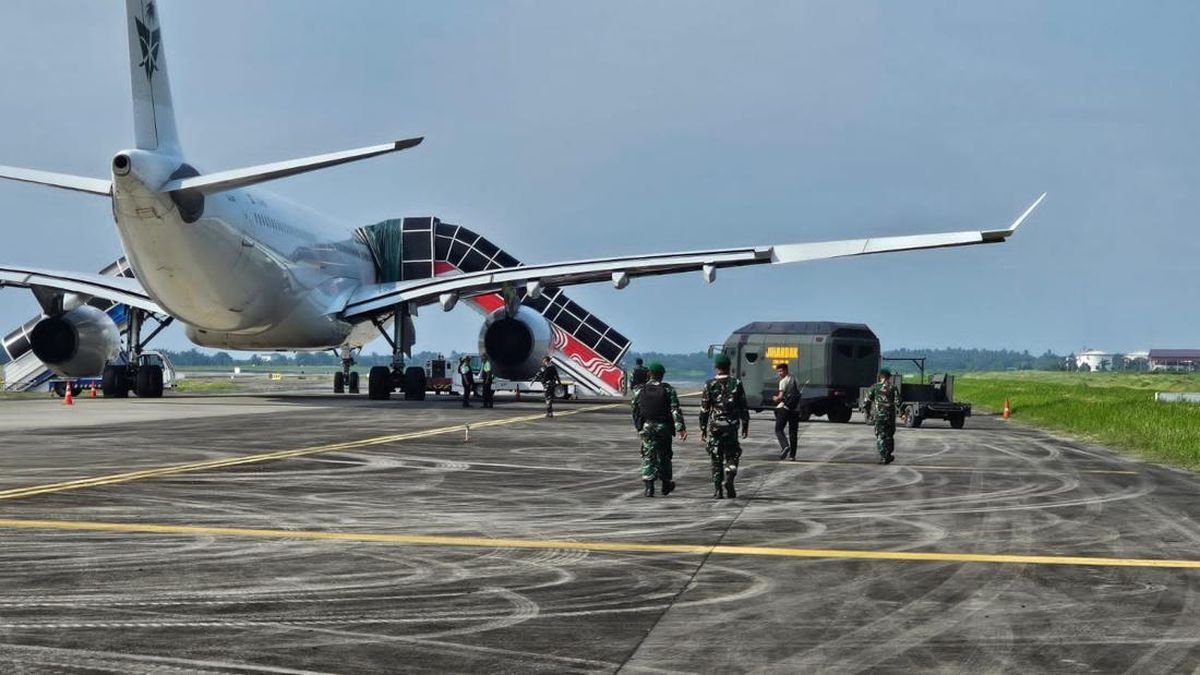 Petugas mengevakuasi penumpang pesawat Saudia Airlines di Bandara Kualanamu setelah adanya ancaman bom, dengan pengamanan ketat TNI dan Brimob.